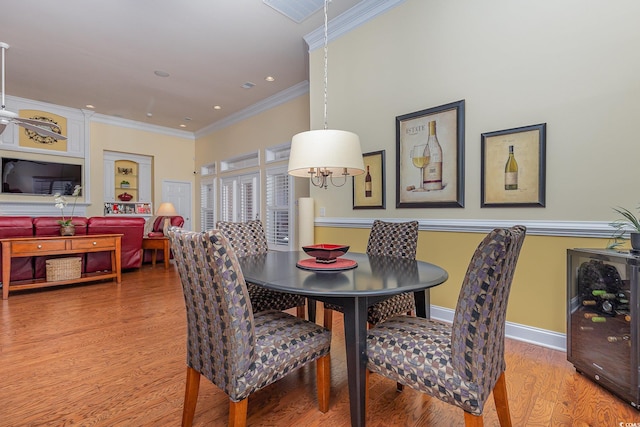 dining space featuring ornamental molding, wine cooler, and light hardwood / wood-style flooring