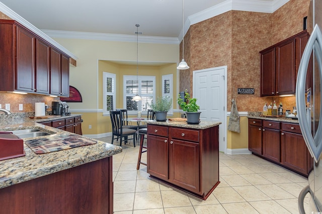 kitchen with light stone countertops, decorative light fixtures, ornamental molding, and sink