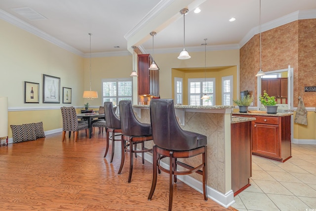 kitchen with plenty of natural light, kitchen peninsula, hanging light fixtures, and ornamental molding