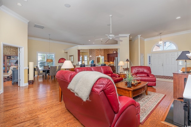 living room with ceiling fan, light wood-type flooring, ornamental molding, and a wealth of natural light