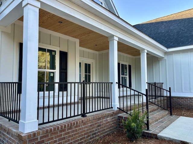 doorway to property with a shingled roof, board and batten siding, and covered porch