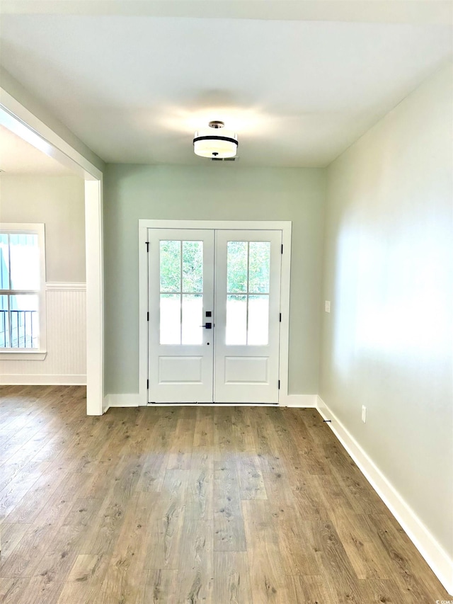 entryway featuring french doors, baseboards, wainscoting, and wood finished floors