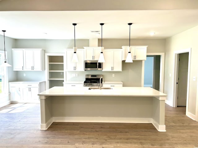 kitchen featuring visible vents, light wood-type flooring, a sink, stainless steel appliances, and an island with sink