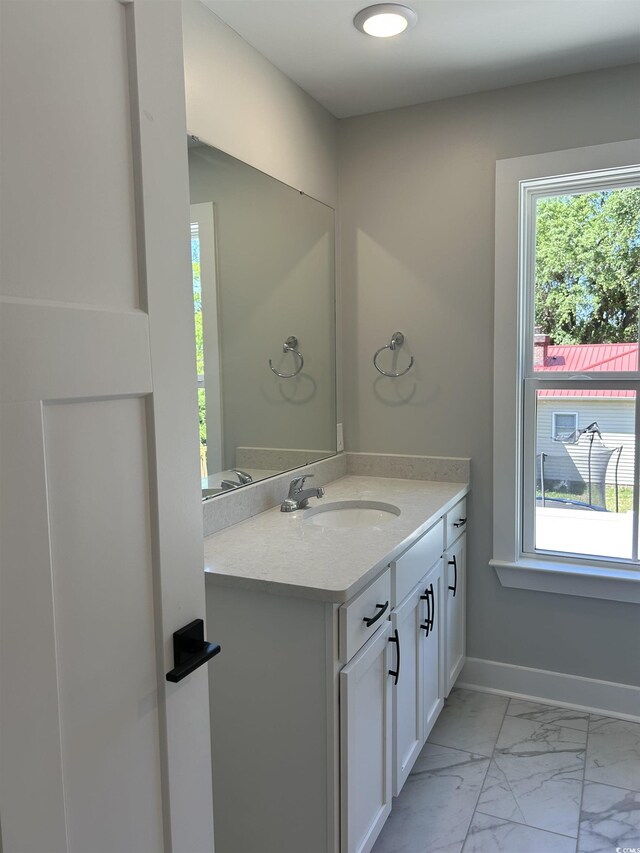 bathroom with vanity, marble finish floor, and baseboards