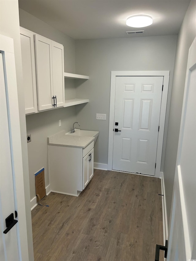 clothes washing area with baseboards, visible vents, a sink, and dark wood-type flooring