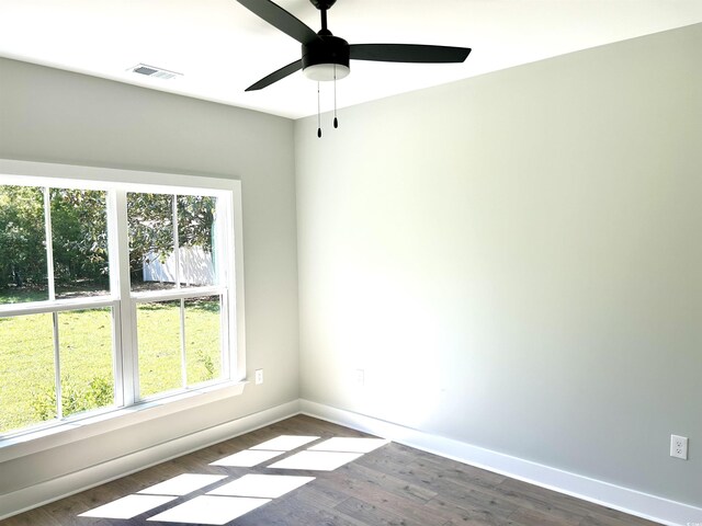 empty room featuring baseboards, plenty of natural light, dark wood finished floors, and visible vents