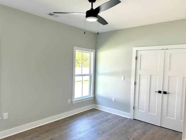 unfurnished bedroom featuring baseboards, visible vents, wood finished floors, and a closet