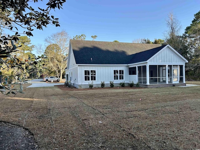 back of house featuring roof with shingles, board and batten siding, and a sunroom