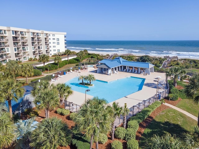 view of pool featuring a patio area, a water view, and a view of the beach