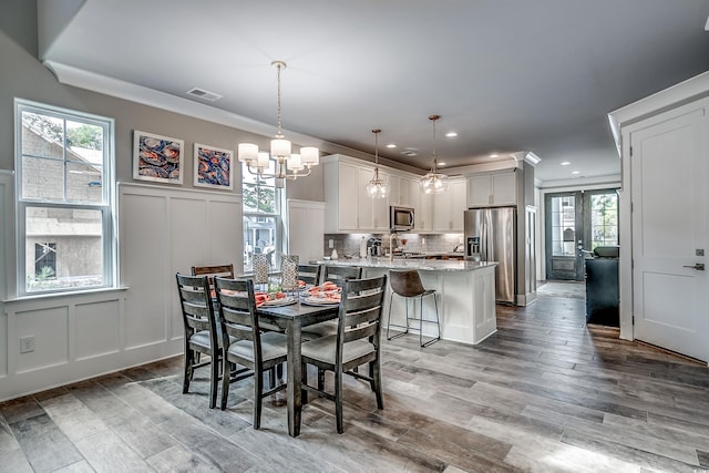 dining area featuring light hardwood / wood-style floors, an inviting chandelier, and ornamental molding