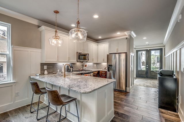 kitchen featuring kitchen peninsula, appliances with stainless steel finishes, pendant lighting, and a healthy amount of sunlight