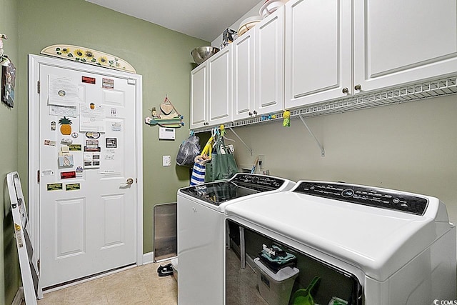 clothes washing area with washer and clothes dryer, light tile patterned flooring, and cabinets