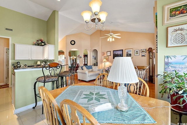 dining space with ceiling fan with notable chandelier, high vaulted ceiling, and light tile patterned flooring