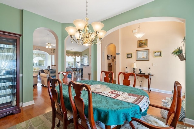 dining room featuring ceiling fan with notable chandelier and hardwood / wood-style flooring