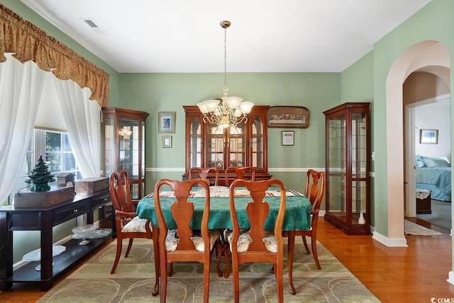 dining space with hardwood / wood-style floors and an inviting chandelier