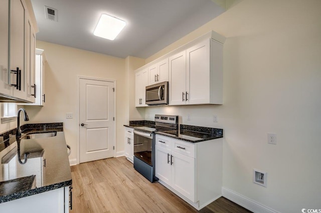 kitchen with white cabinets, light wood-style flooring, visible vents, and stainless steel appliances