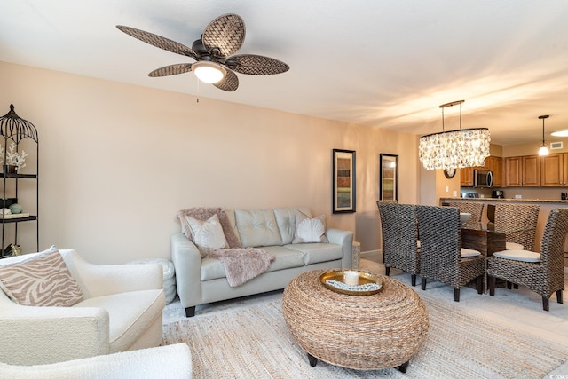 carpeted living room with ceiling fan with notable chandelier