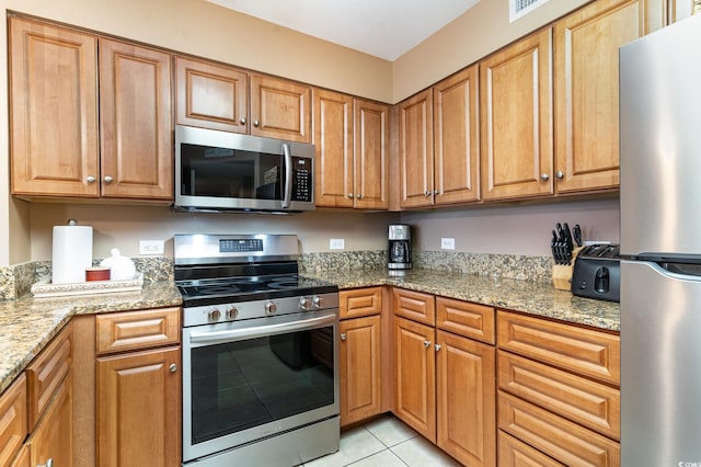 kitchen with light stone countertops, stainless steel appliances, and light tile patterned flooring