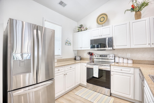 kitchen with appliances with stainless steel finishes, white cabinetry, and vaulted ceiling