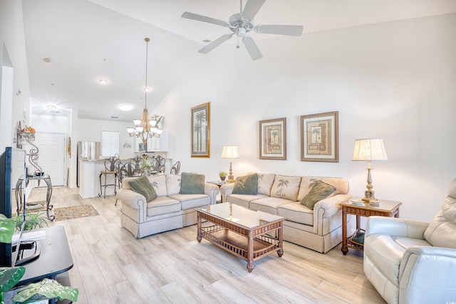 living room with ceiling fan with notable chandelier, light wood-type flooring, and high vaulted ceiling