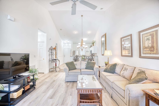 living room featuring ceiling fan with notable chandelier, light wood-type flooring, and high vaulted ceiling