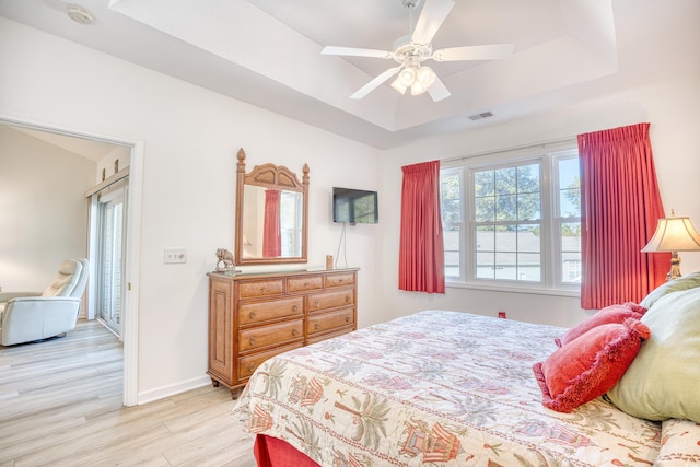 bedroom featuring a tray ceiling, ceiling fan, and light hardwood / wood-style flooring