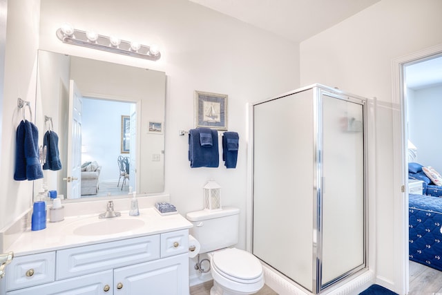 bathroom with hardwood / wood-style floors, vanity, toilet, and a shower with door