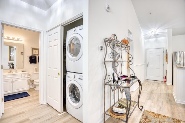 laundry area featuring light wood-type flooring and stacked washer / dryer