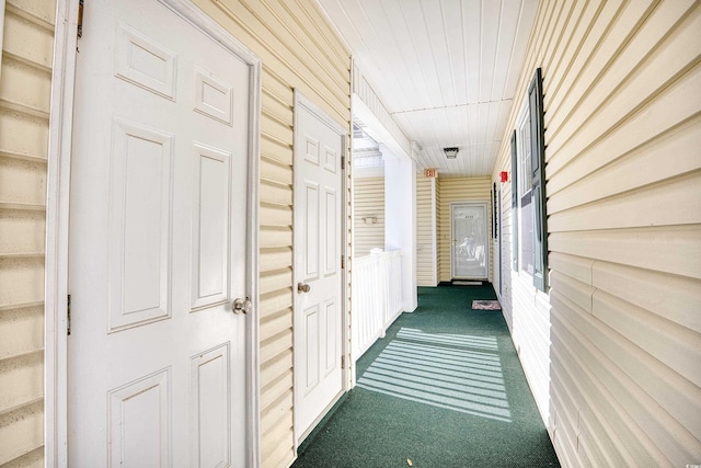 hallway featuring dark colored carpet