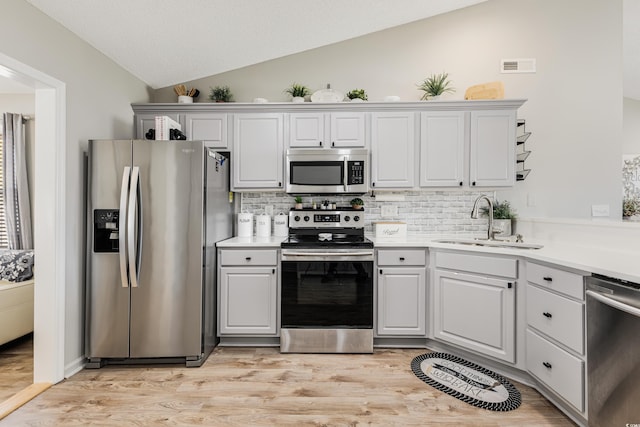 kitchen featuring sink, white cabinets, lofted ceiling, and appliances with stainless steel finishes