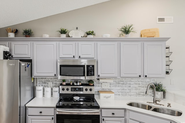 kitchen with decorative backsplash, sink, vaulted ceiling, and appliances with stainless steel finishes