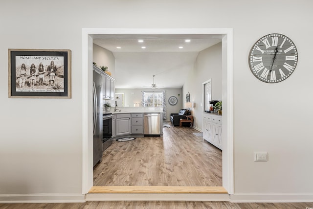 kitchen featuring appliances with stainless steel finishes, light wood-type flooring, gray cabinetry, ceiling fan, and sink