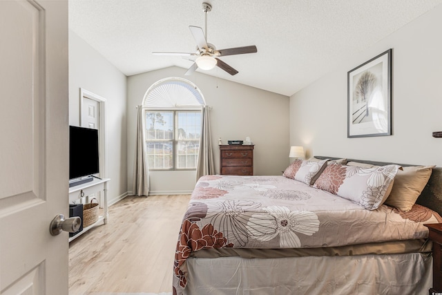 bedroom featuring a textured ceiling, ceiling fan, light hardwood / wood-style flooring, and lofted ceiling