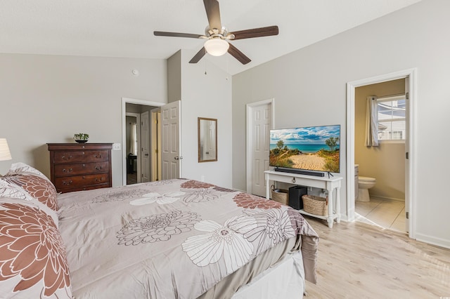 bedroom with ensuite bathroom, ceiling fan, light hardwood / wood-style flooring, and vaulted ceiling