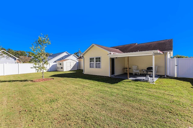 back of house with a lawn, a storage shed, and a patio