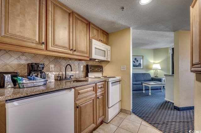 kitchen featuring a textured ceiling, sink, light tile patterned flooring, and white appliances