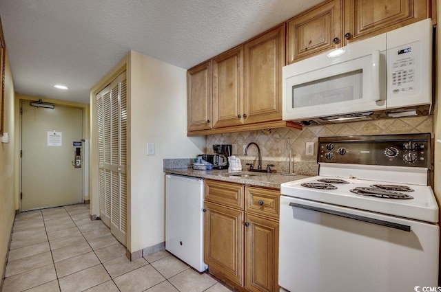 kitchen with white appliances, sink, decorative backsplash, light tile patterned floors, and a textured ceiling