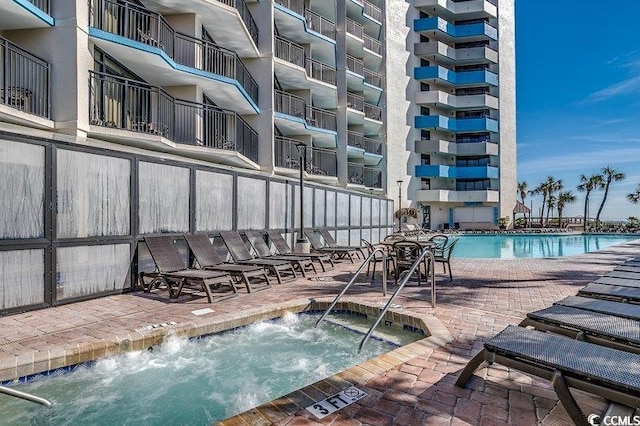 view of swimming pool featuring a patio and a hot tub