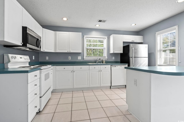 kitchen featuring a sink, visible vents, white cabinetry, appliances with stainless steel finishes, and dark countertops