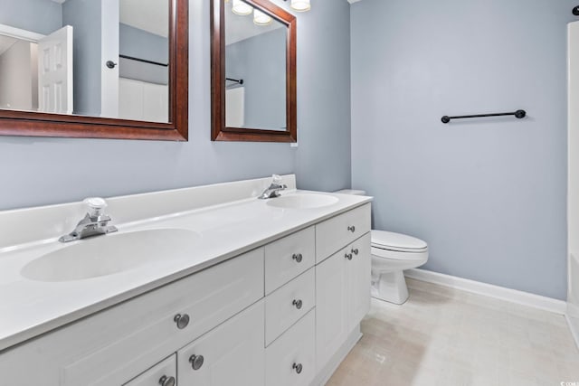 bathroom with baseboards, a sink, toilet, and double vanity