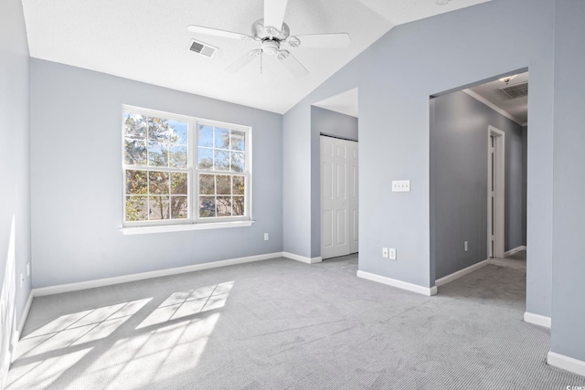 unfurnished bedroom featuring light colored carpet, lofted ceiling, visible vents, and baseboards