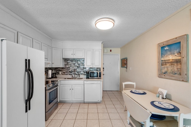 kitchen featuring sink, stainless steel appliances, light tile patterned floors, backsplash, and white cabinets