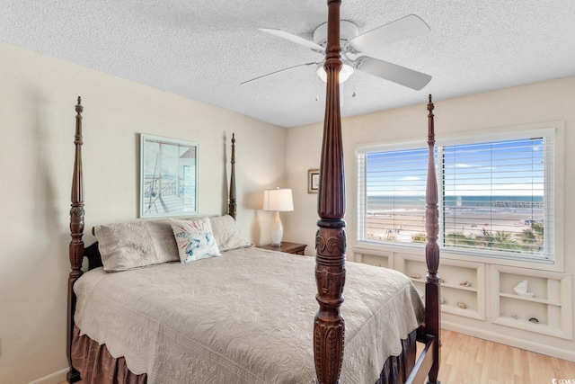 bedroom with ceiling fan, light wood-type flooring, and a textured ceiling