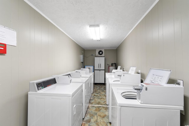 washroom with independent washer and dryer, a textured ceiling, and wooden walls