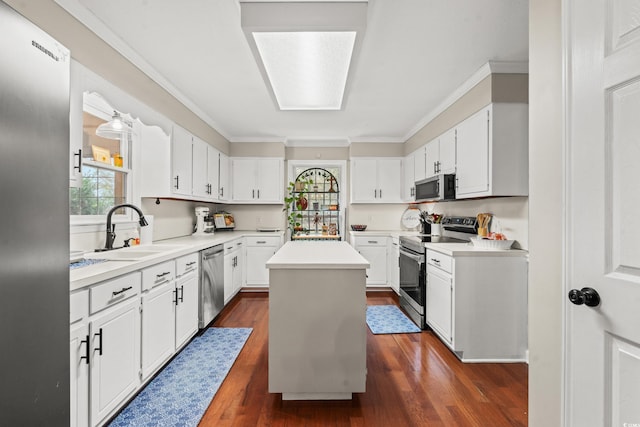 kitchen with a kitchen island, appliances with stainless steel finishes, a sink, ornamental molding, and dark wood-type flooring