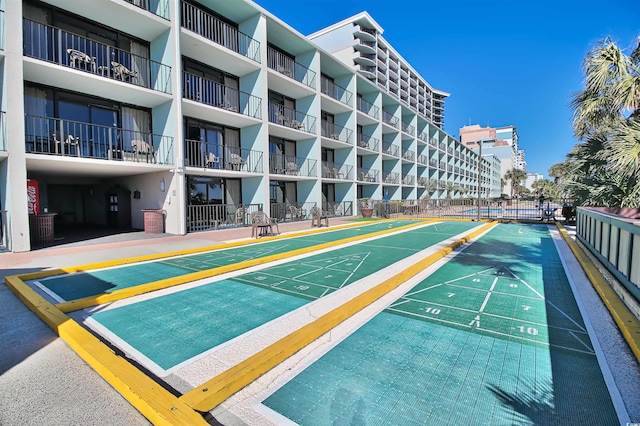 view of community with shuffleboard and fence