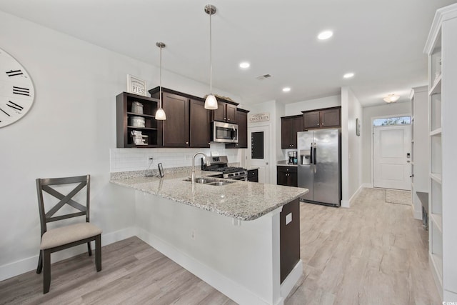 kitchen featuring appliances with stainless steel finishes, light wood-type flooring, dark brown cabinetry, sink, and pendant lighting