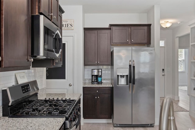 kitchen featuring decorative backsplash, light wood-type flooring, stainless steel appliances, and light stone counters