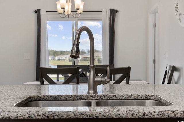 interior space with light stone countertops, a notable chandelier, and sink