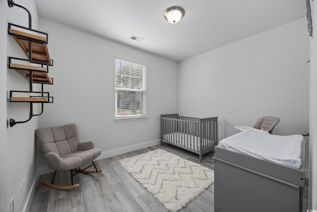 bedroom featuring light hardwood / wood-style floors and a nursery area